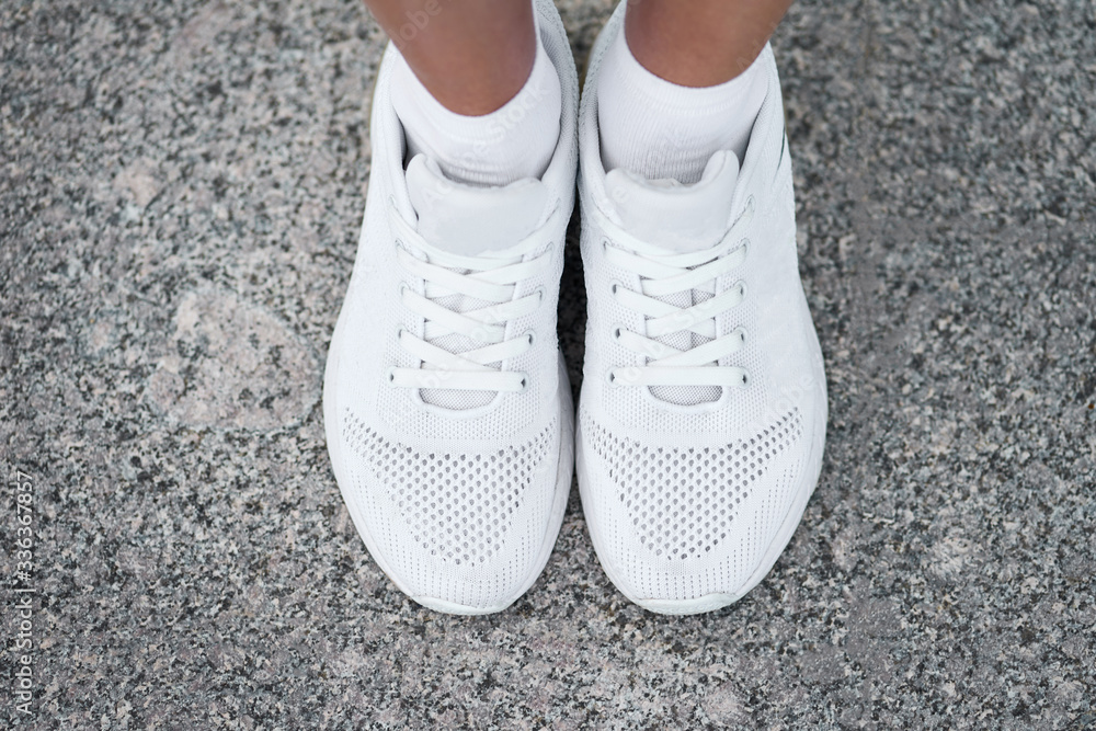 Closeup top view of female legs in stylish white sneakers. Active woman on a training. Ready to start.