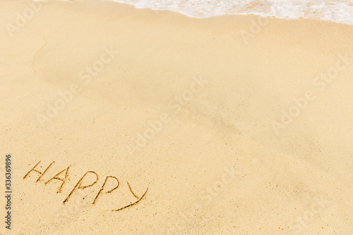 Happy sign and wave on a sandy beach. Background close up.