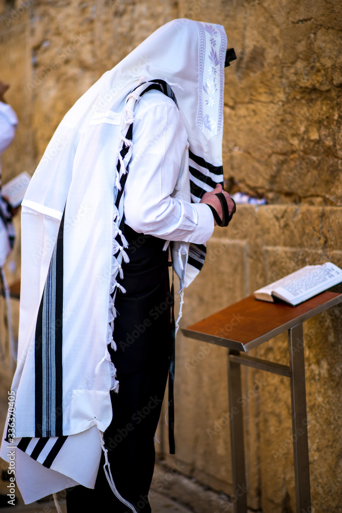 Orthodox Jew praying at the Western Wall, wearing the tallit prayer shawl and tefillin