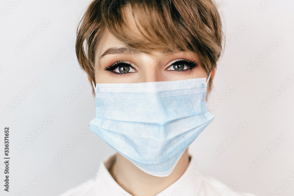 Woman in a white shirt wearing medical mask. White background Woman in a white shirt wearing medical mask. White background