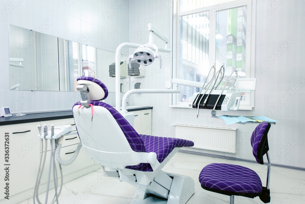 Interior of a modern dental clinic. The dentist's chair is ready to go. Special medical equipment in a white medical light