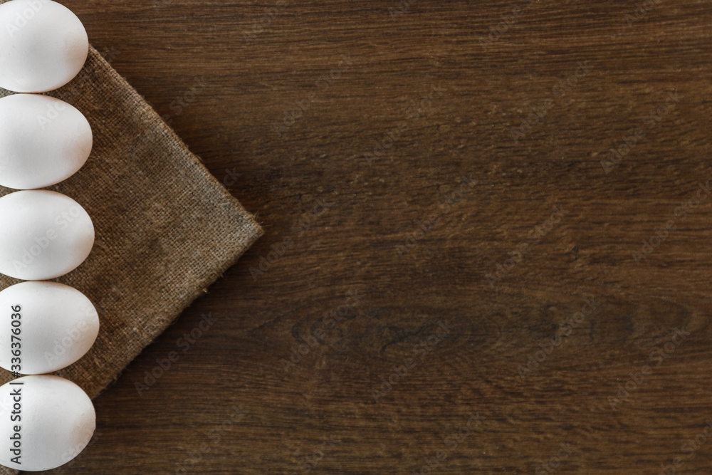 Fototapeta premium Easter white eggs line on brown wooden background and sackcloth. 