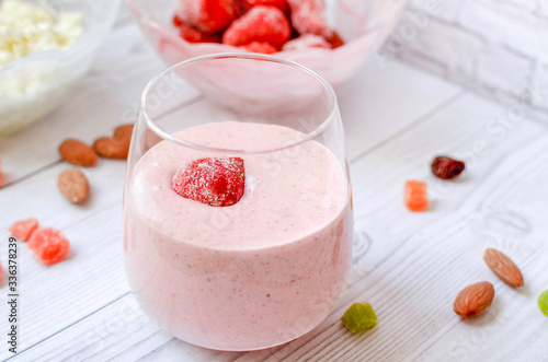 Strawberry smoothie with berry in a glass on a white wooden table. Healthy eating.