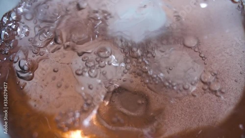 Close-up of fizzy drink pouring into glass with ice cubes on slow motion photo