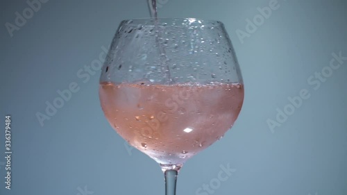 Drink pouring in rotating glass with ice cubes photo