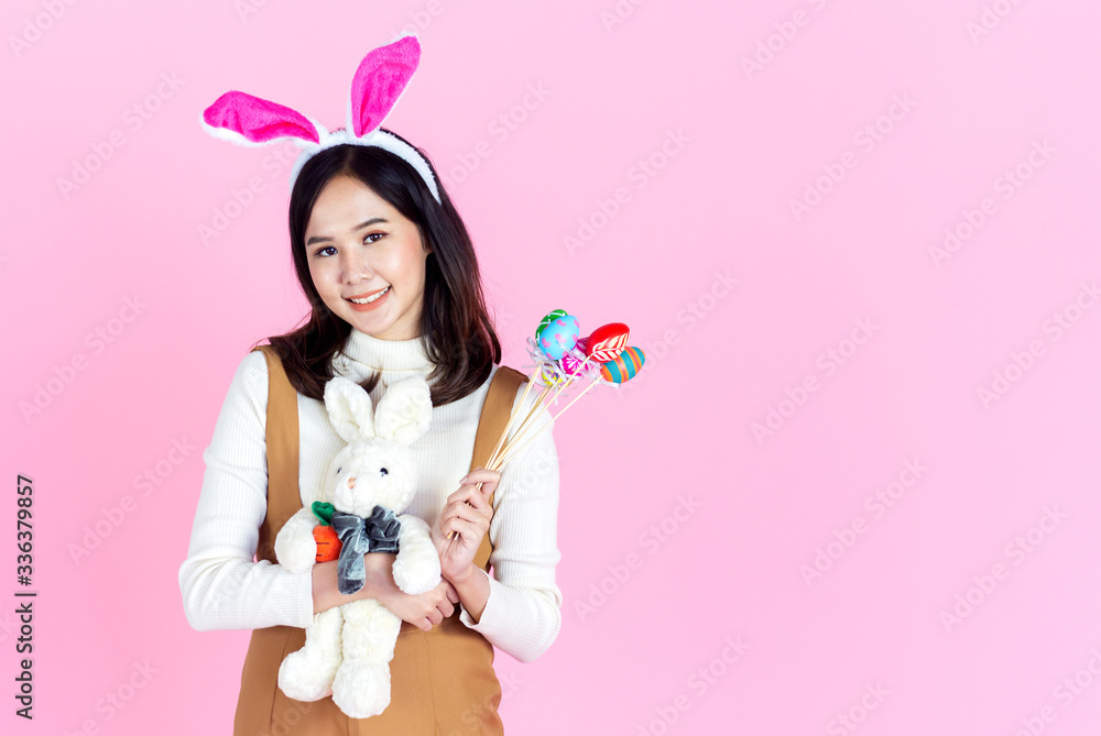 Asian young woman wearing bunny holding a colorful egg basket for Easter on a pink background. girl smiled happily copy space. Asian young woman wearing bunny holding a colorful egg basket for Easter on a pink background. girl smiled happily copy space.