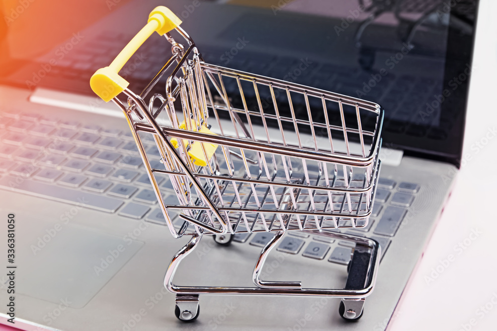 Small shopping trolley standing on laptop keyboard