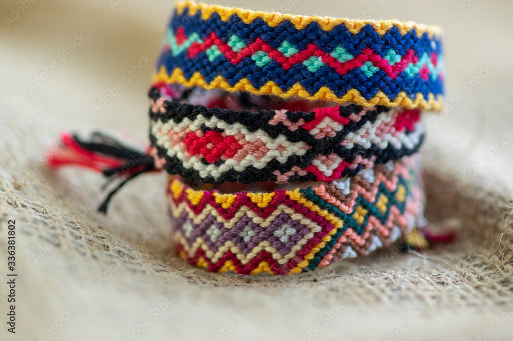 Group of handmade homemade colorful natural woven bracelets of friendship isolated on jute background Group of handmade homemade colorful natural woven bracelets of friendship isolated on jute background