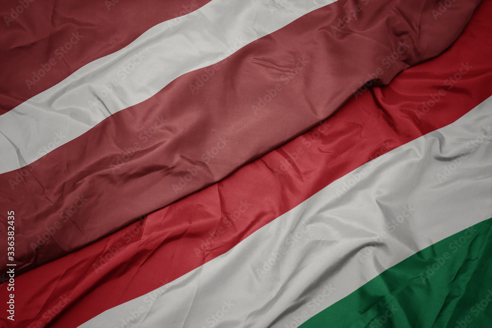waving colorful flag of hungary and national flag of latvia. waving colorful flag of hungary and national flag of latvia.