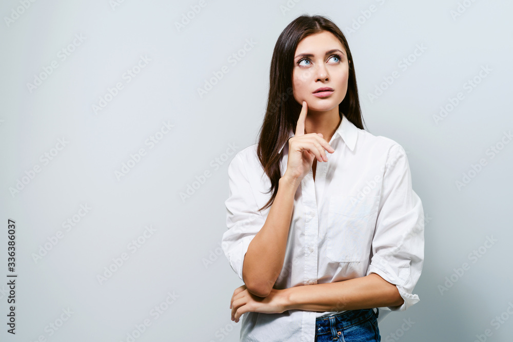 An occasion for reflection. Woman thought about something. Young brunette girl on a white background shows different emotions An occasion for reflection. Woman thought about something. Young brunette girl on a white background shows different emotions