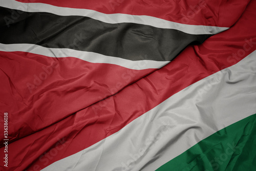 waving colorful flag of hungary and national flag of trinidad and tobago.