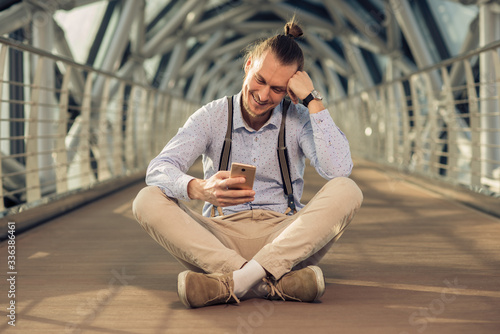 Tableau sur toile young businessman smiling at the message in your phone
