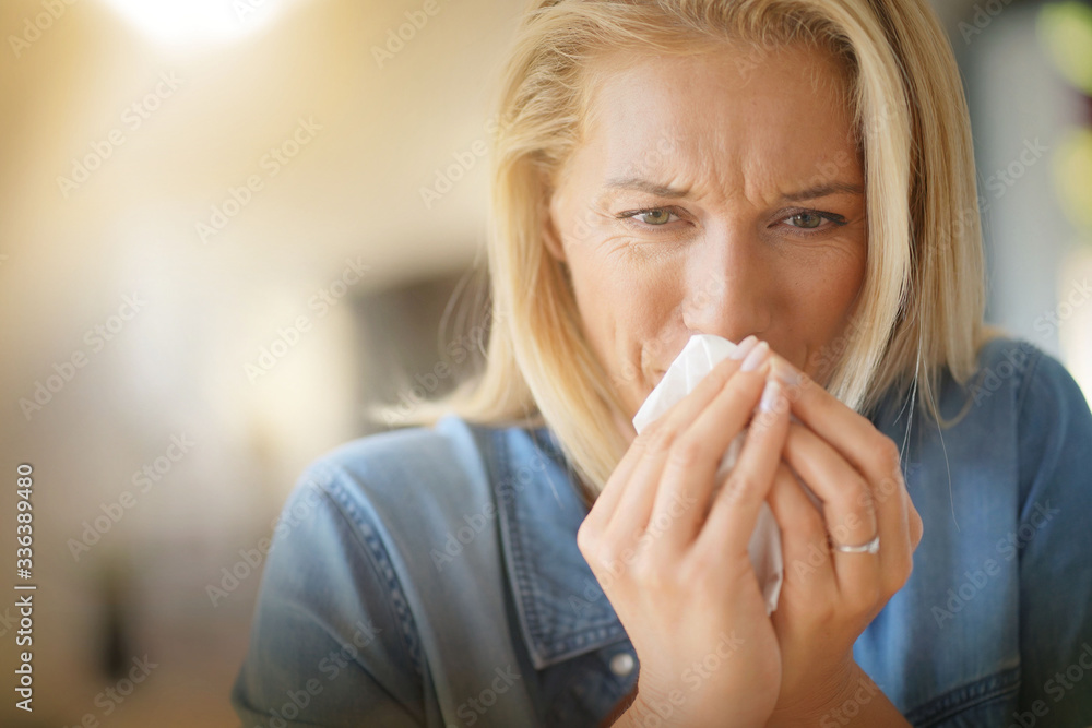 Middle-aged woman with allergy blowing her nose Middle-aged woman with allergy blowing her nose