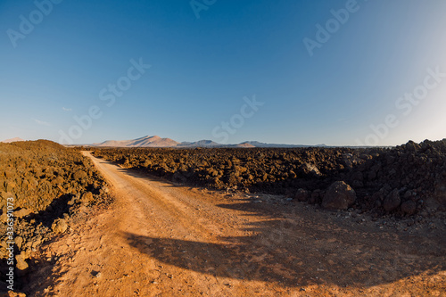 Aerial view of lava fields with dirty road and volcanos. Lanzarote, Canary Islands.