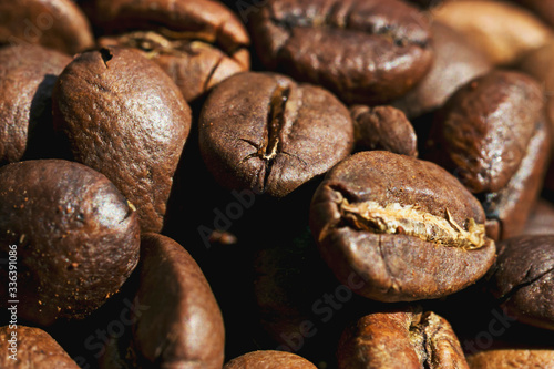 Roasted coffee beans are scattered on the table close-up. Photo in bright sunlight in the morning. © OlPhoto