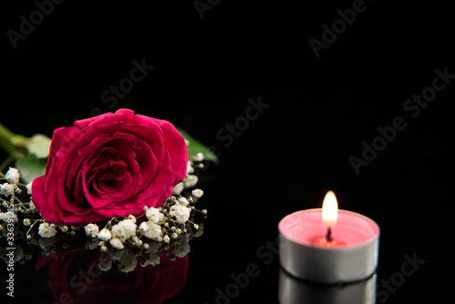 Candle, red rose and white gypsophila with black background, copy space