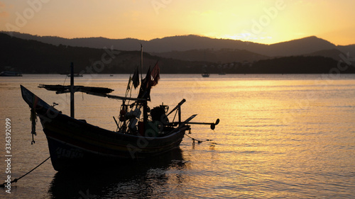 boat near the shore against the backdrop of mountains and beautiful sunset. Romantic atmosphere. Calm and pacifying scene.