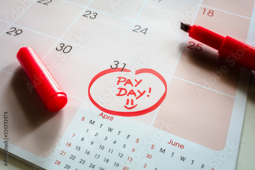Payday end of month date on calendar with red marker and circled day of salary photo