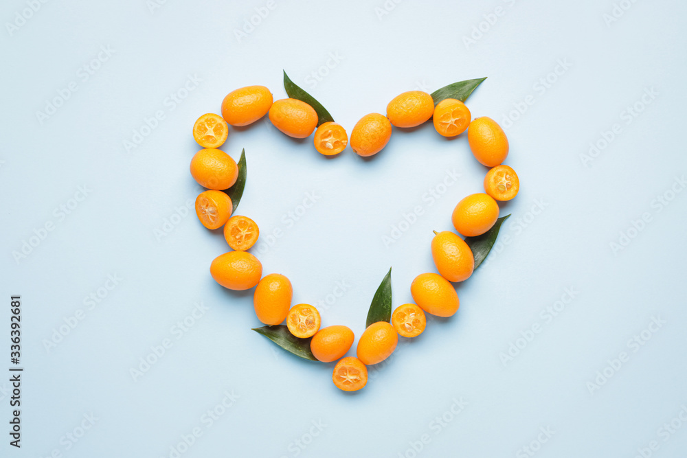 Heart made of tasty kumquat fruit on color background Heart made of tasty kumquat fruit on color background