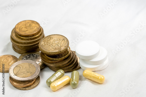 concept of healthcare system recovery for COVID-19 crisis in EU, euro coins stacked and pills on clean and nice white textile fabric.
