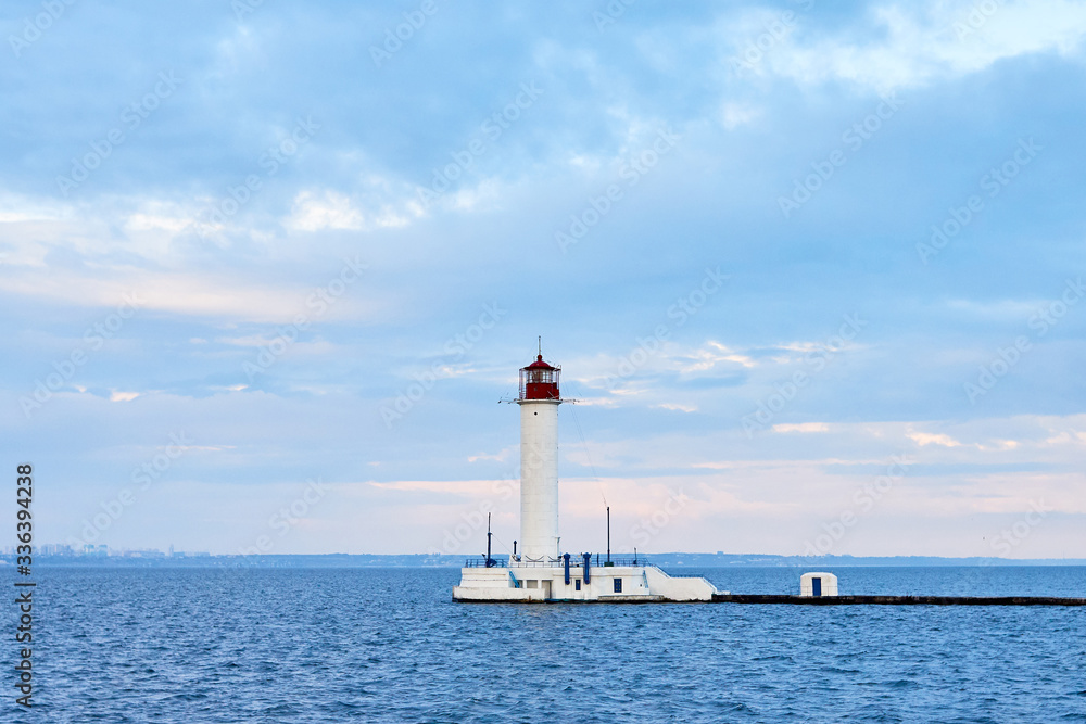 Red and white lighthouse in sea at sunset, copy space. Summer seascape with light house. Black sea