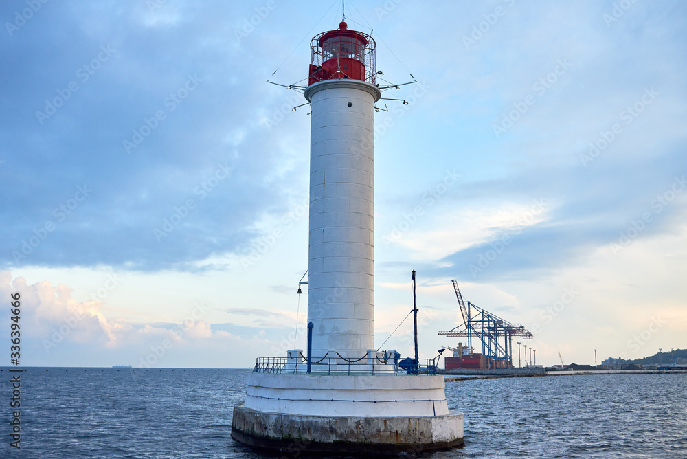 Red and white lighthouse in sea at sunset, copy space. Summer seascape with light house. Black sea Red and white lighthouse in sea at sunset, copy space. Summer seascape with light house. Black sea