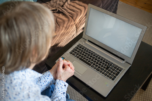 connecting online during coronavirus pandemic elderly woman with laptop chatting in their living room