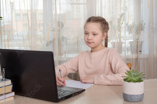 Schoolgirl studying at home. Young girl using laptop at home. Distance education, home education. Self isolation concept © lizaelesina