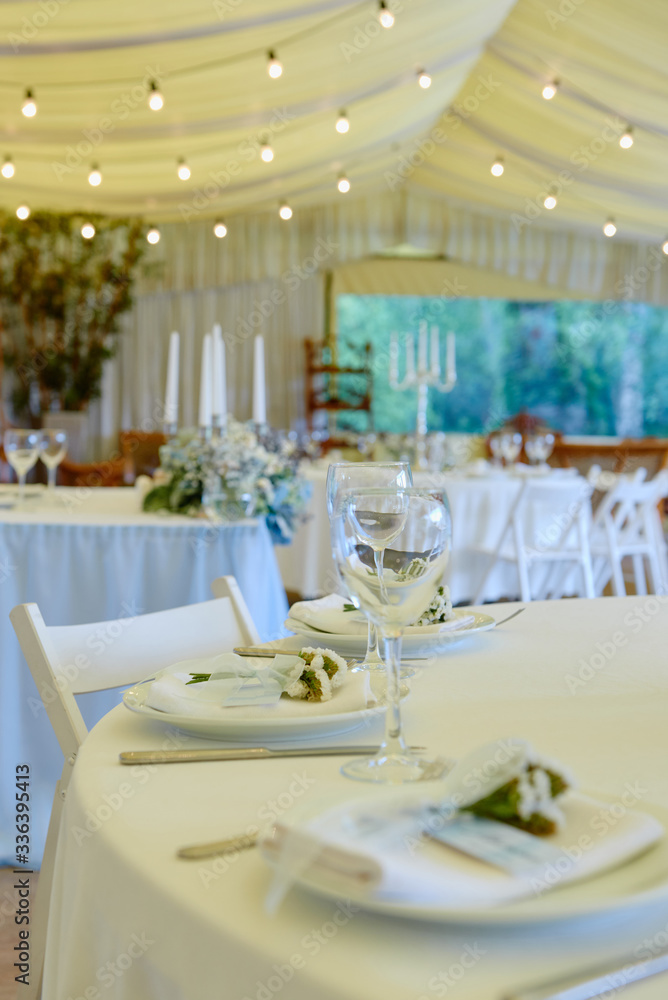Table set with blank guest card, plate with white napkin and cutlery on table, copy space. Place setting at wedding reception. Table served for wedding banquet in restaurant Table set with blank guest card, plate with white napkin and cutlery on table, copy space. Place setting at wedding reception. Table served for wedding banquet in restaurant