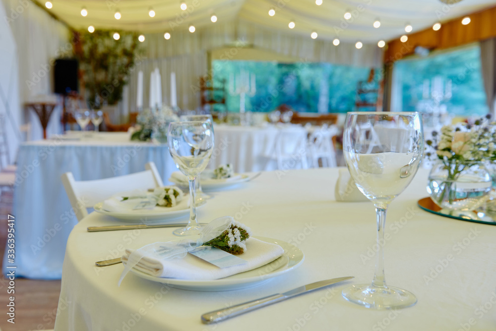 Table set with blank guest card, plate with white napkin and cutlery on table, copy space. Place setting at wedding reception. Table served for wedding banquet in restaurant Table set with blank guest card, plate with white napkin and cutlery on table, copy space. Place setting at wedding reception. Table served for wedding banquet in restaurant