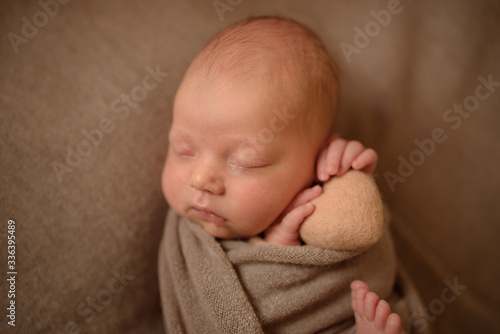 Newborn girl sleeping with a dried heart in her hands.