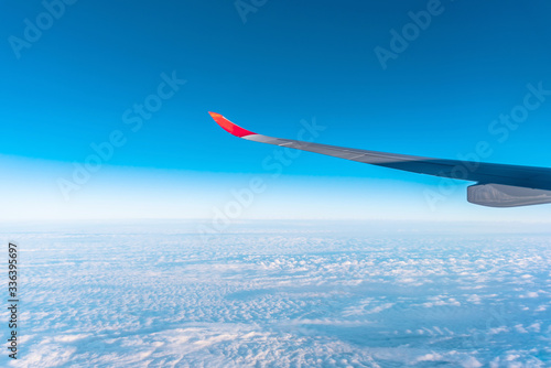 Airplane wing above beautiful blue cloudy sky in the morning (view from airplane)