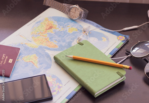 Traveler's accessories, Essential vacation items, Travel concept background. Planning a vacation trip and looking for information or booking a hotel using smartphone and writing notes. Selective focus