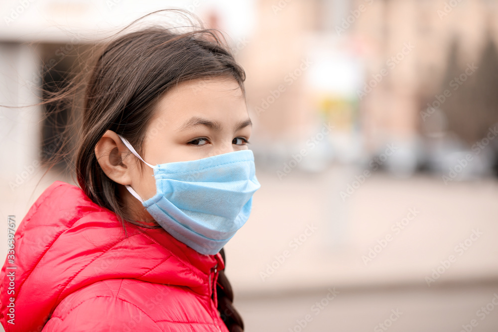 Little Asian girl wearing protective mask on city street. Concept of epidemic Little Asian girl wearing protective mask on city street. Concept of epidemic