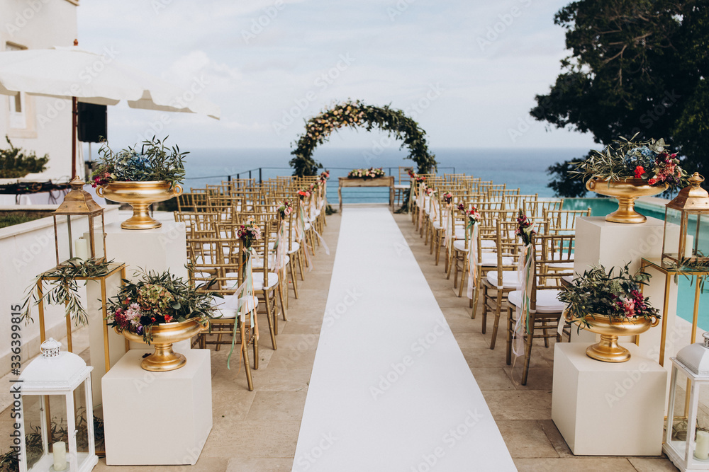 Wedding decorations. The ceremony area in the villa by the pool overlooking the sea is decorated with flower arrangements, golden vases and candles