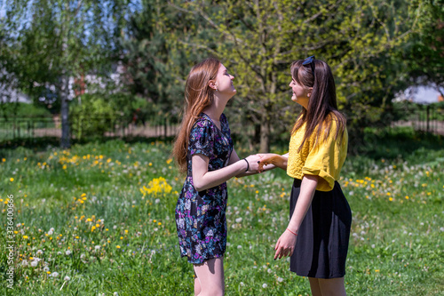 Young girls have fun time in the park. The sisters communicate and share secrets. Happy sisters are enjoying a warm spring day