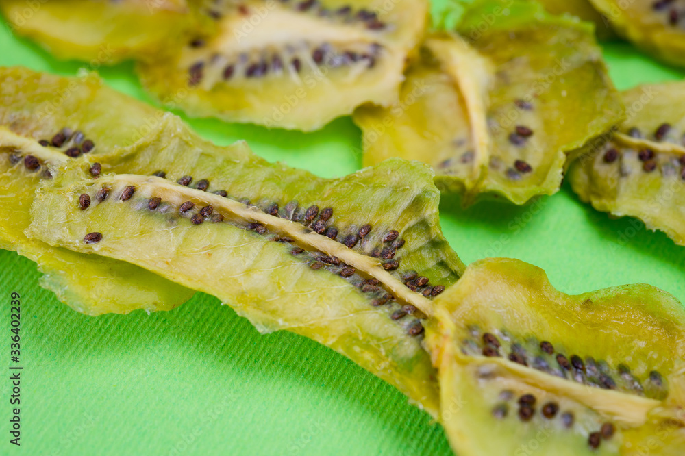 Dried kiwi chips, sliced in thin circles. Shot on a green background. Background for vegetarianism and healthy eating. Dried kiwi chips, sliced in thin circles. Shot on a green background. Background for vegetarianism and healthy eating.