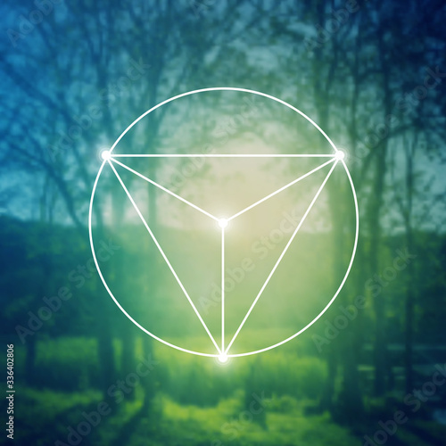 Merkaba sacred geometry spiritual new age futuristic illustration with interlocking circles, triangles and glowing particles in front of blurry natural photographic background
