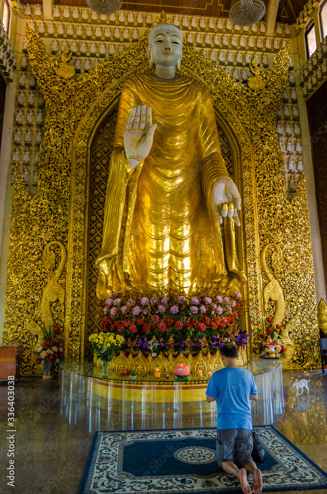 man in the temple prays to a Buddha