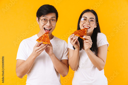 Image of cheerful multinational couple smiling and eating pizza