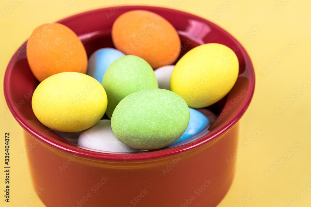Small Easter eggs in a red cup on yellow background Small Easter eggs in a red cup on yellow background