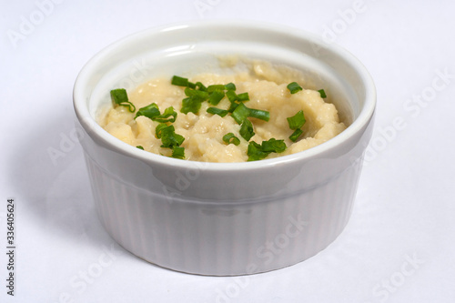 Plate of mashed potatoes with steamed cutlet and pickled cucumbers with green onions on white background