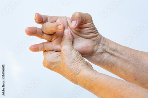 Trigger Finger lock on middle finger, Senior woman's left hand massaging her right hand Suffering from pain on white background, Close up shot, Office syndrome, Healthcare, Massage, Asian body concept photo