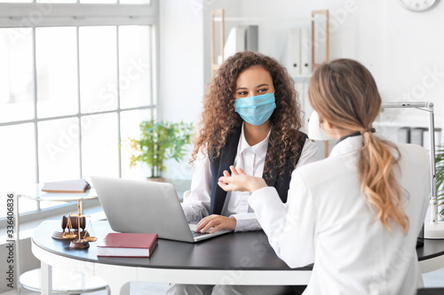 Female lawyer in protective mask working with client in office photo