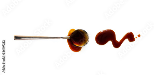Spoon with teriyaki and soy sauce splash isolated on white background, top view. Close-up seasoning and dip photo