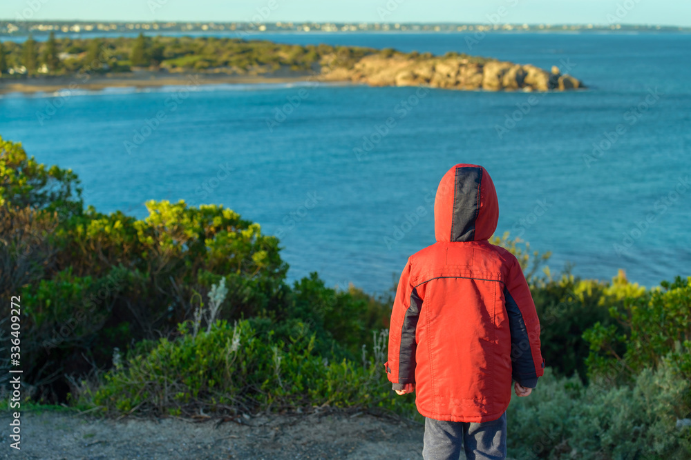 Little lonely child standing on the cliff and watching the sea, Port Elliot, South Australia