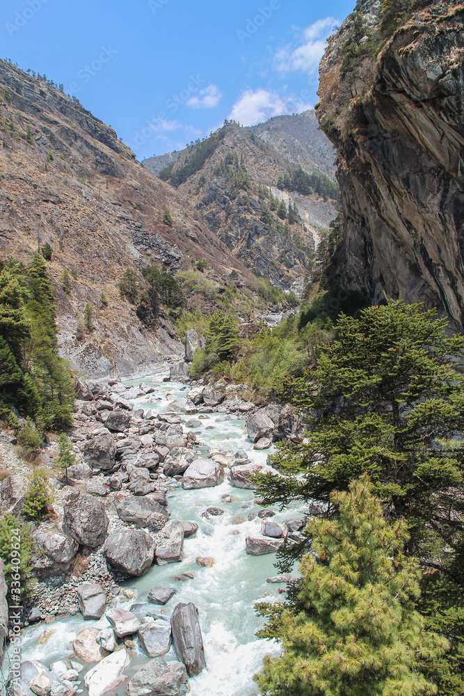 Beautiful mountain valley with flowing river in Himalayas in the day near Thyangboche village. Mountainside is covered by coniferous trees. Beautiful landscape. Theme of travel in Nepal. Beautiful mountain valley with flowing river in Himalayas in the day near Thyangboche village. Mountainside is covered by coniferous trees. Beautiful landscape. Theme of travel in Nepal.
