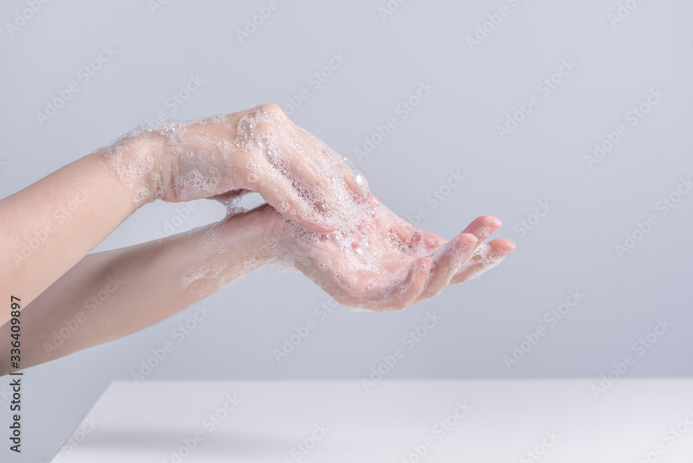 Washing hands. Asian young woman using liquid soap to wash hands, concept of hygiene to protective pandemic coronavirus isolated on gray white background, close up. Washing hands. Asian young woman using liquid soap to wash hands, concept of hygiene to protective pandemic coronavirus isolated on gray white background, close up.