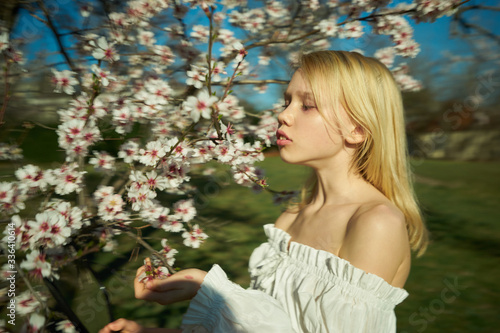 girl, blonde, half-turn, in a white dress, on a background of a blossoming tree © Сергей Кристев