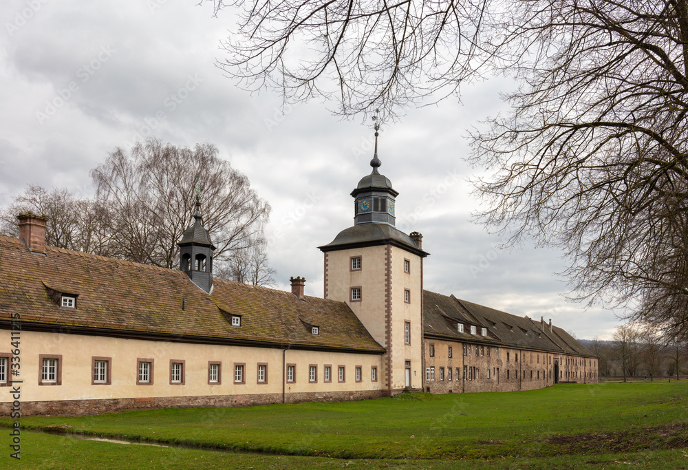 Fototapeta premium The Corvey Castle in eastern North Rhine-Westphalia near the town of Höxter. You can see the western outside with a tower. It is a cloudy winter day, the trees have no leaves.
